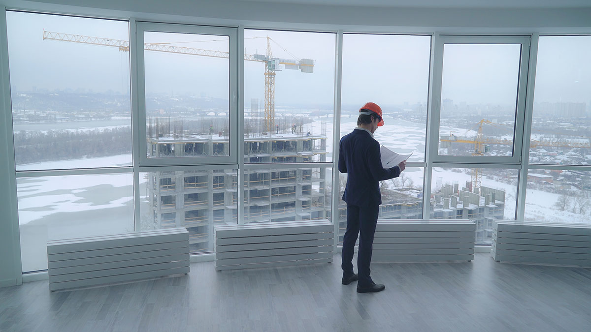 property developer standing in empty building with construction out the window